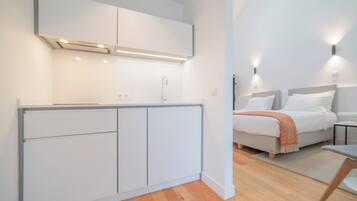 Habitació d'hotel moderna amb armari integrat, un llit amb capçalera, taules de nit i una petita zona de seients.
