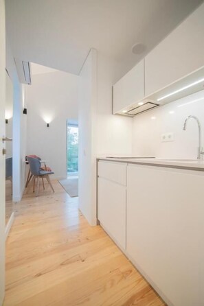 A modern kitchen with white cabinetry, a countertop, and a built-in oven.
