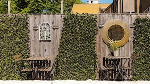 Een houten omheining met een decoratief raam en een ronde spiegel.