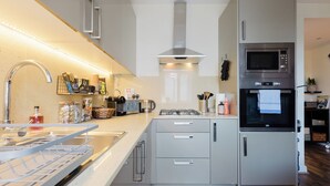 Een moderne keuken met een roestvrijstalen fornuis, een magnetron en een inbouwoven.