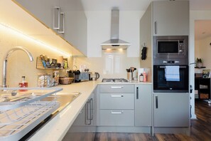Eine moderne Küche mit einem Edelstahlherd, einer Mikrowelle und einem eingebauten Backofen.