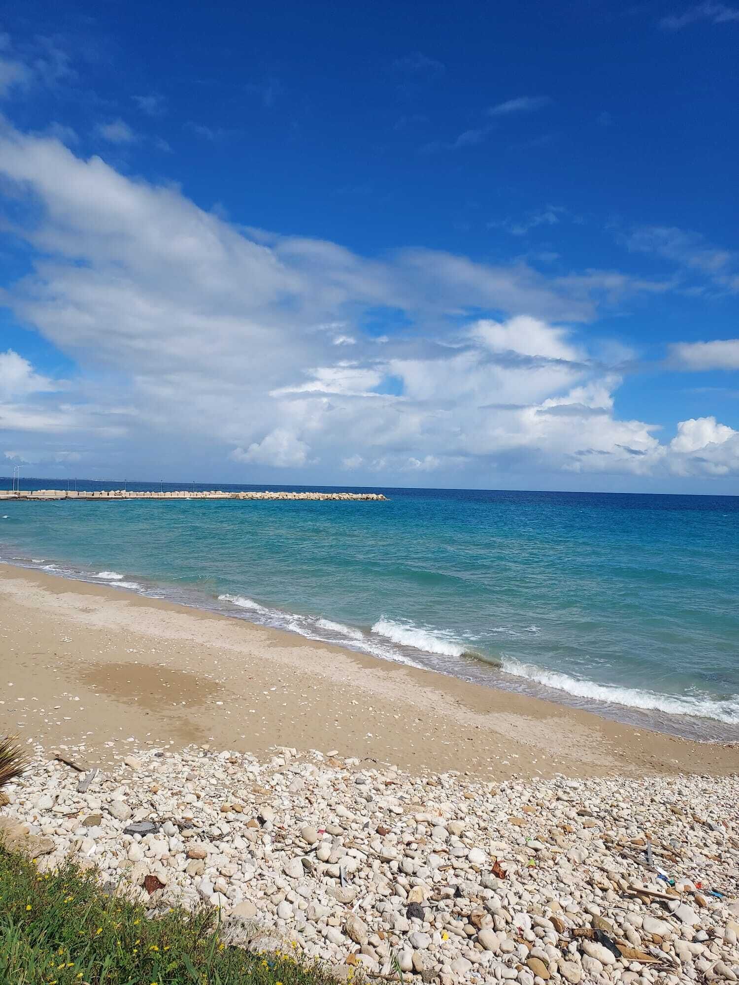 Ein Strand mit felsigem Ufer und blauem Himmel.