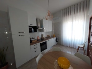 Eine moderne Küche mit weißen Schränken, einer Holztischplatte und einem Essbereich mit einem runden Tisch.
