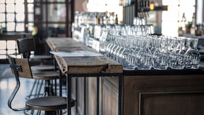 A bar area with a long wooden counter and multiple empty glasses lined up. - Boutique Hotel Kolbeck (Vienna)