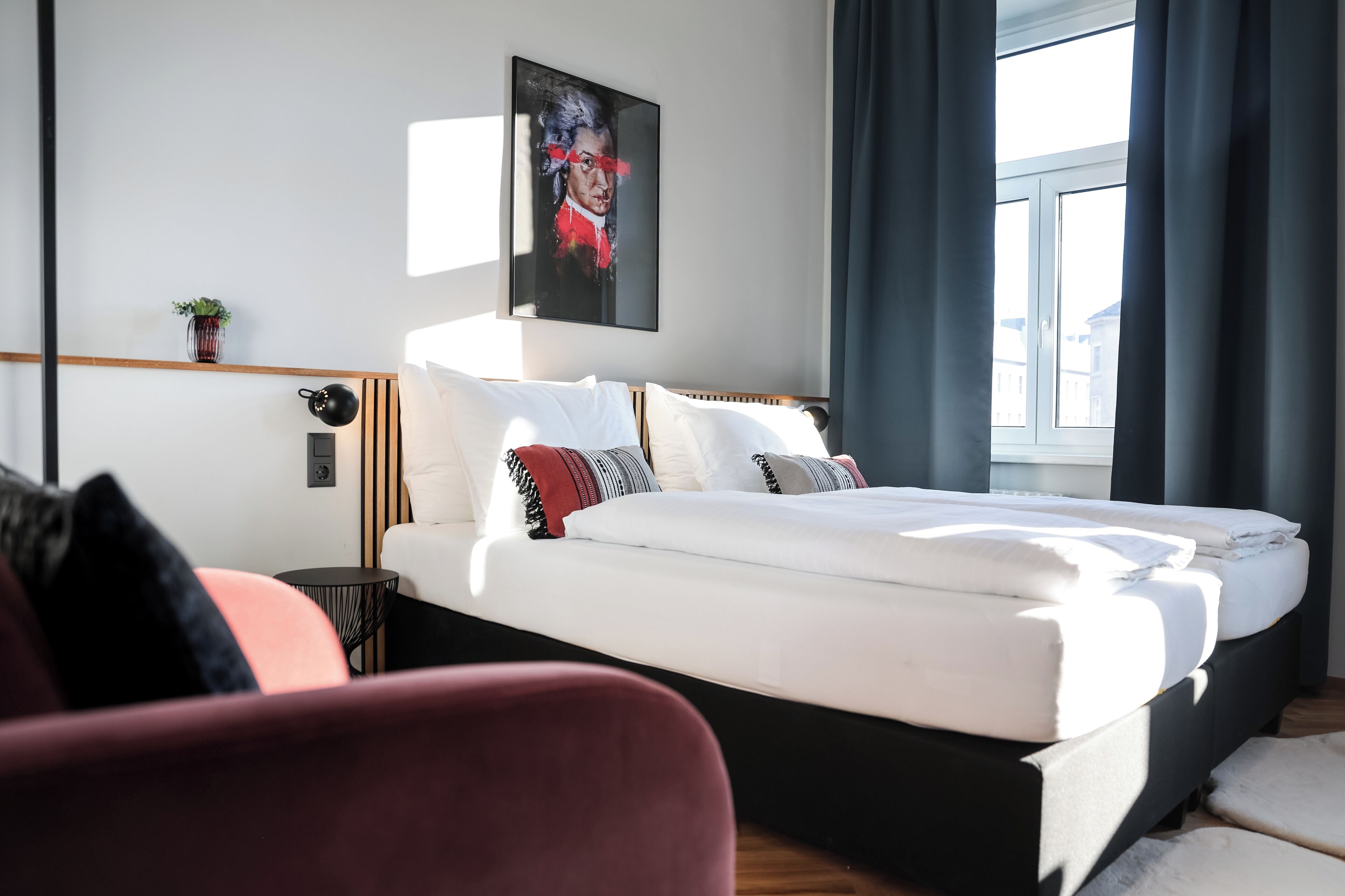 Ein modernes Hotelzimmer mit einem großen Bett, einem Nachttisch, einem kleinen Topfpflanzen und einem Vorhangfenster.