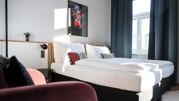 Ein modernes Hotelzimmer mit einem großen Bett, einem Nachttisch, einem kleinen Topfpflanzen und einem Vorhangfenster.