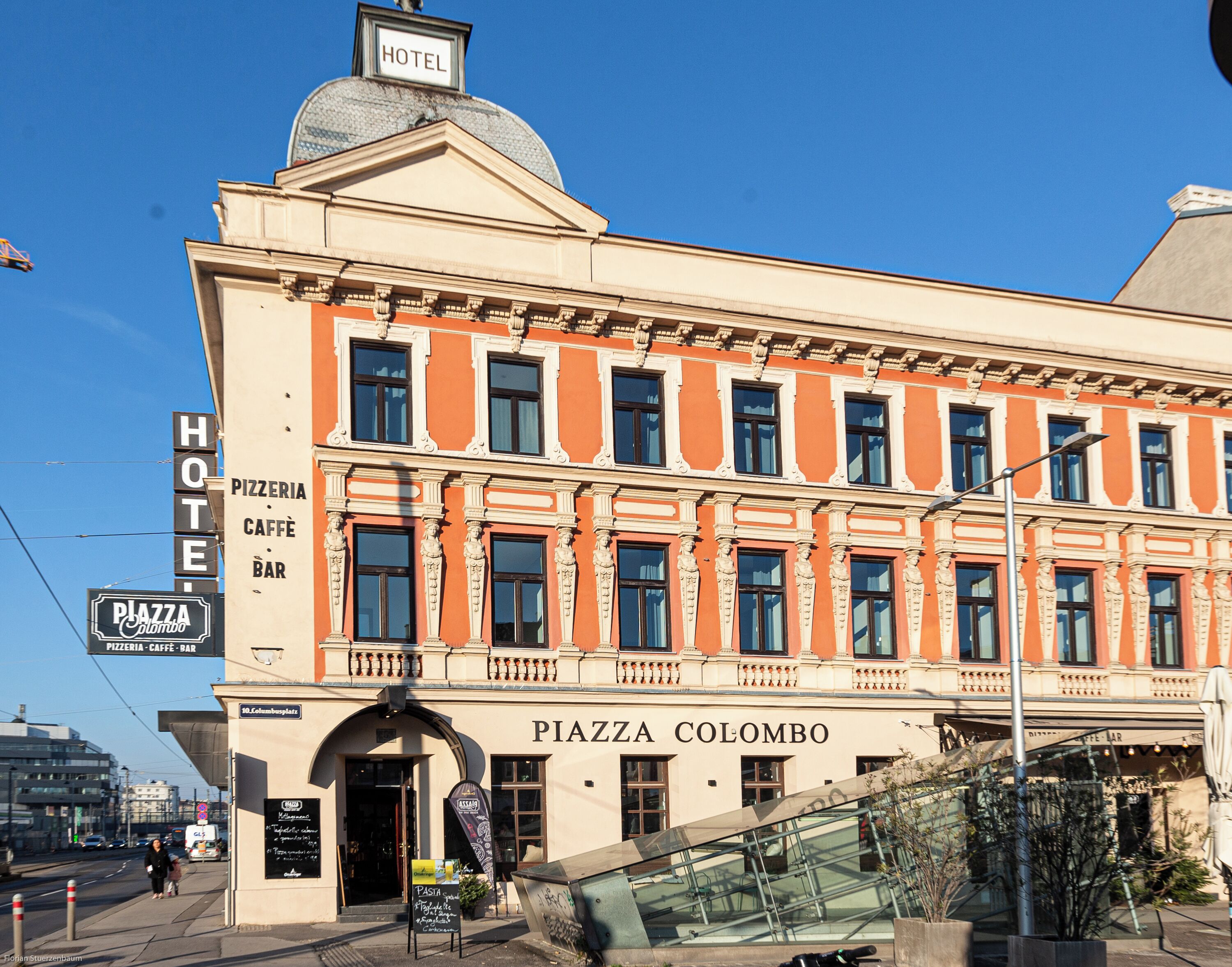 Ein historisches Gebäude mit einem Schild, auf dem 'Piazza Colombo' und 'Hotel' stehen, das ein Hotel und Restaurant anzeigt.