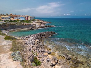 A coastal area with rocky terrain, clear blue waters, and a row of colorful buildings. - Villa Brisa by Interhome (Colònia Sant Pere)