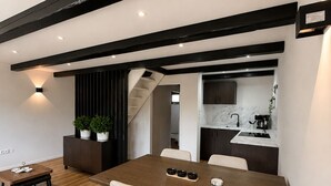 A modern dining area with a wooden table and chairs, a small side table, and a staircase leading to an upper level.