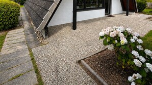 A modern house with a sloped roof, a visible number '11' on the side, and a gravel driveway.