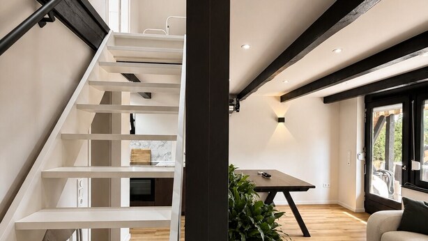 A modern interior with a staircase, a dining area, and a seating space.