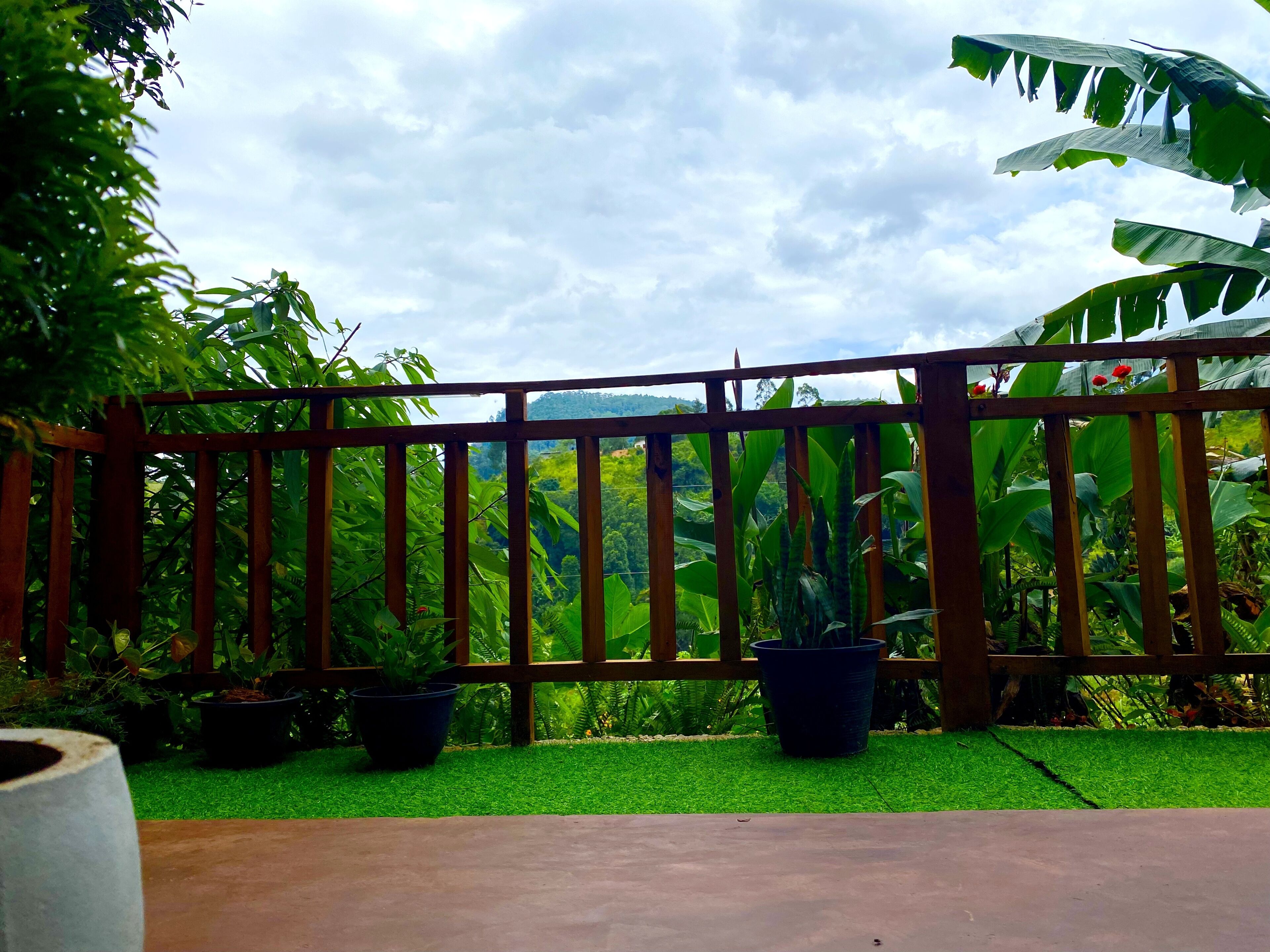 A wooden fence with potted plants and a view of a lush green landscape.