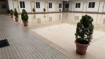 A clean, tiled courtyard with potted plants and a row of doors.