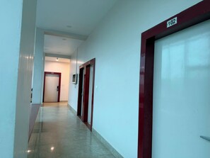 A corridor with a red door marked '102' and a security camera. - Devki Grand Hotel (Gwalior)