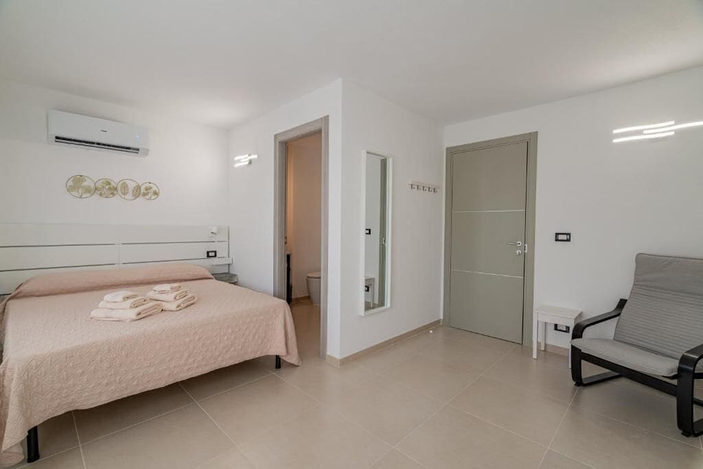 Un dormitorio con cama, una silla, un armario y un equipo de aire acondicionado.