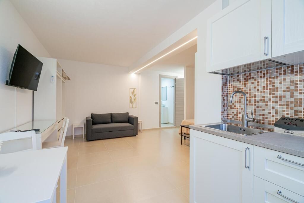 A modern kitchen with white cabinets, a tiled backsplash, and a built-in sink.