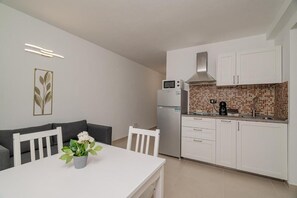 Una cocina compacta con gabinetes blancos, un microondas y una cafetera.
