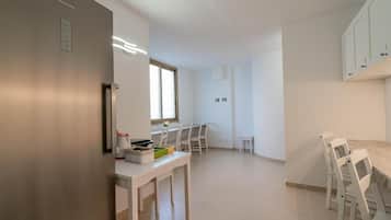 A modern kitchen with white cabinets, a dining area with a table and chairs, and a window providing natural light.