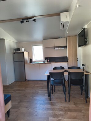 A compact kitchen with a refrigerator, microwave, and a small dining area with a table and chairs.