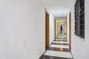 A corridor with a checkered floor pattern, leading to a room with a window. - Super Collection O Manjari -Mundhwa Road (Pune)