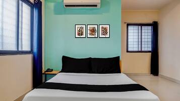 A hotel room with a bed, a nightstand, a phone, and three framed pictures on the wall.
