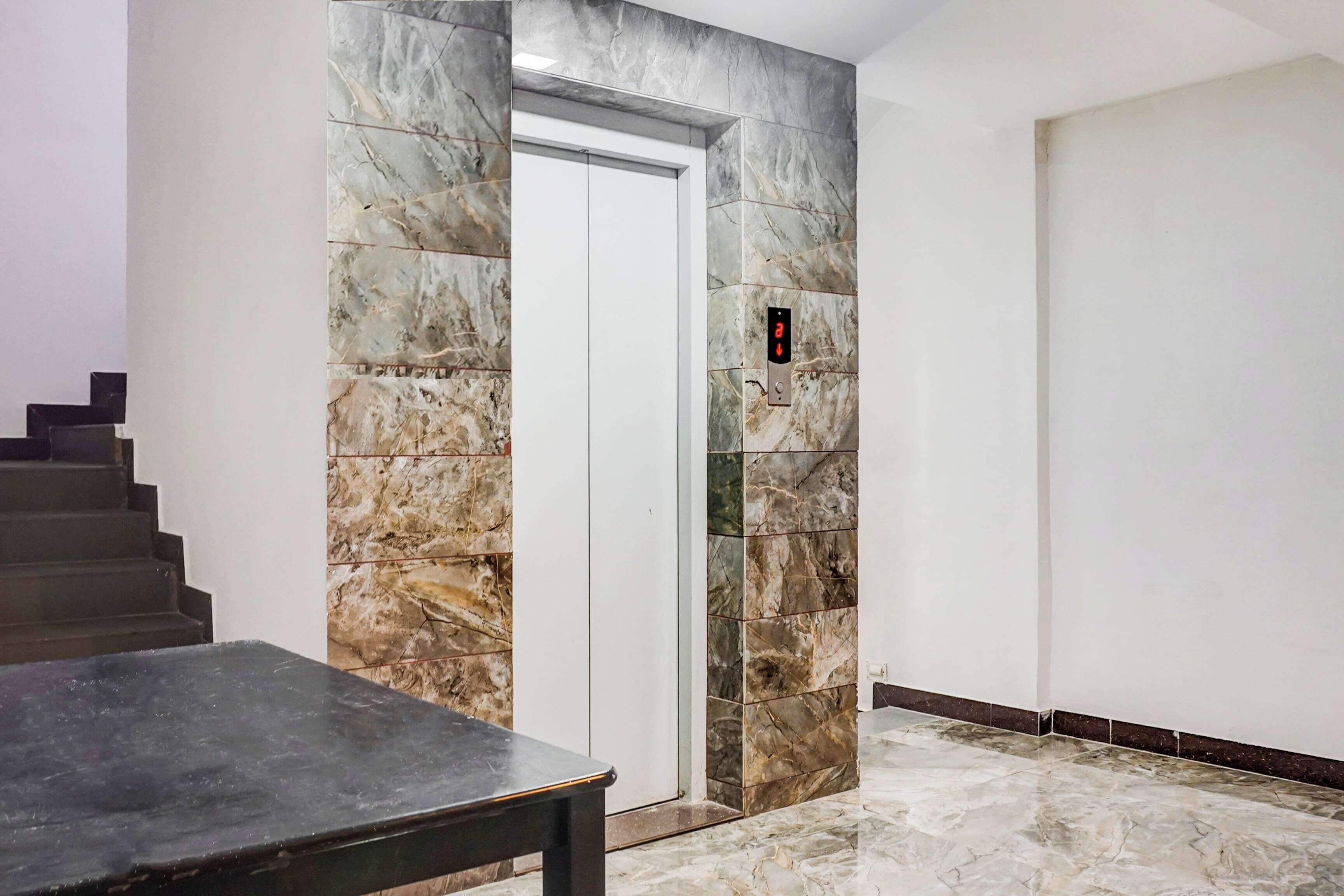 Pared de mármol con una puerta y un panel de control de ascensor.