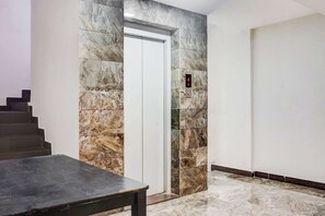 A marble wall with a door and an elevator control panel. - Super Collection O Manjari -Mundhwa Road (Pune)