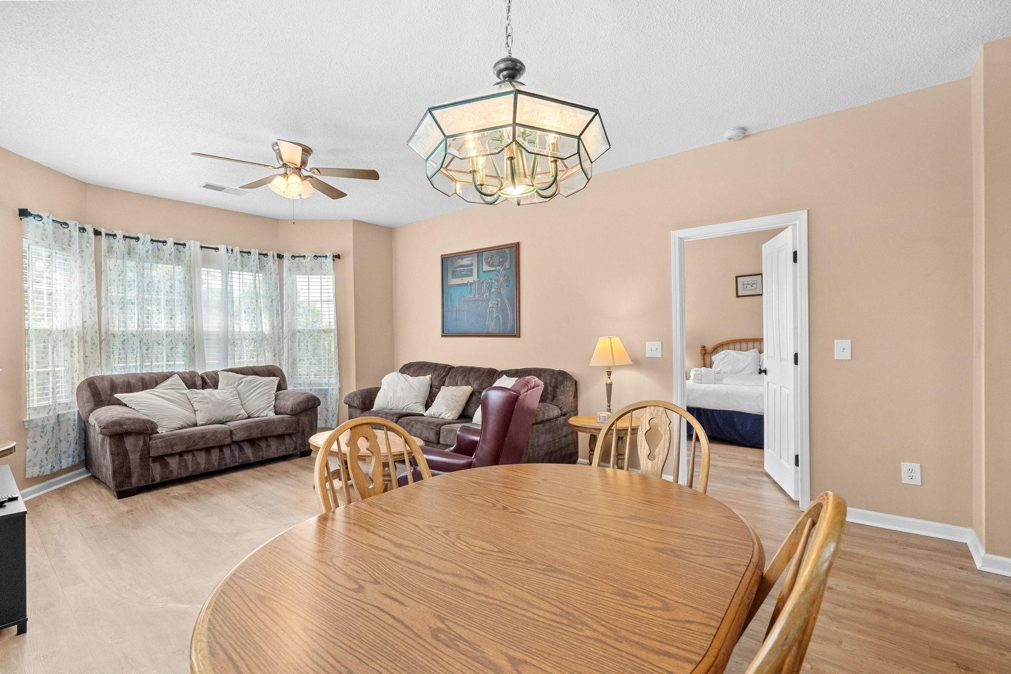 A living room with a ceiling fan, a dining table with chairs, two sofas, and a lamp.