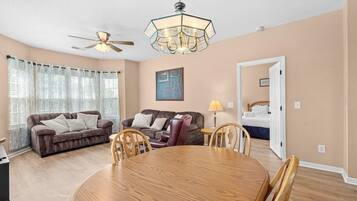 A living room with a ceiling fan, a dining table with chairs, two sofas, and a lamp.