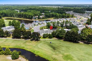 A residential area with houses, a golf course, and a body of water.