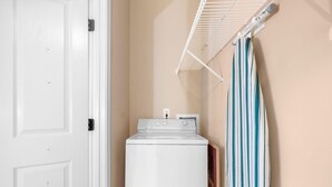 A laundry area with a white dryer, a hanging rack, and a striped towel. - The Victorian Golf Tee at Legends (Myrtle Beach)