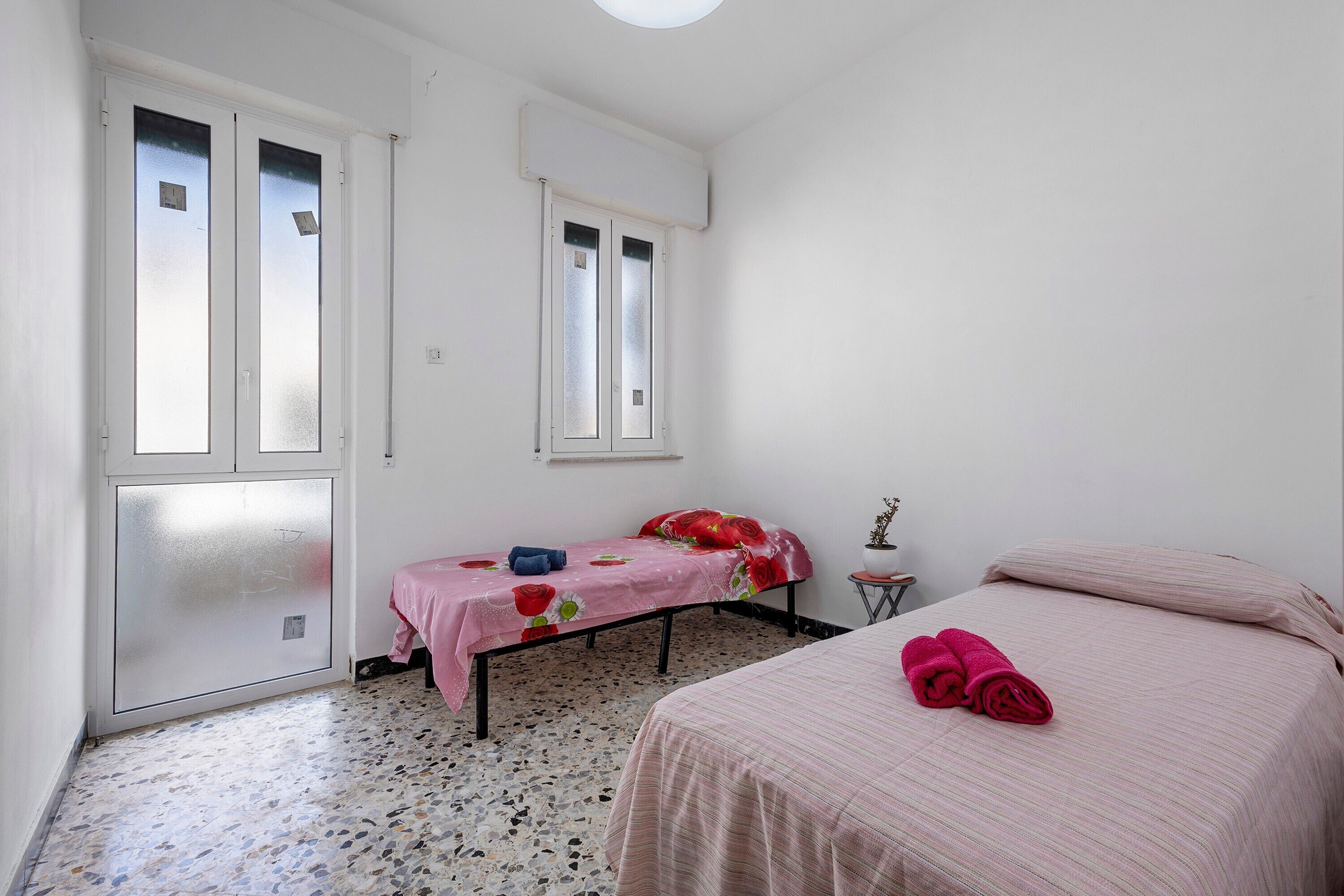 Una habitación pequeña y limpia, con cama, ventana y puerta.