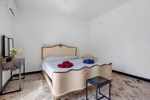 Una cama con cabecera decorativa, una mesita de noche con un jarrón de flores y una silla.