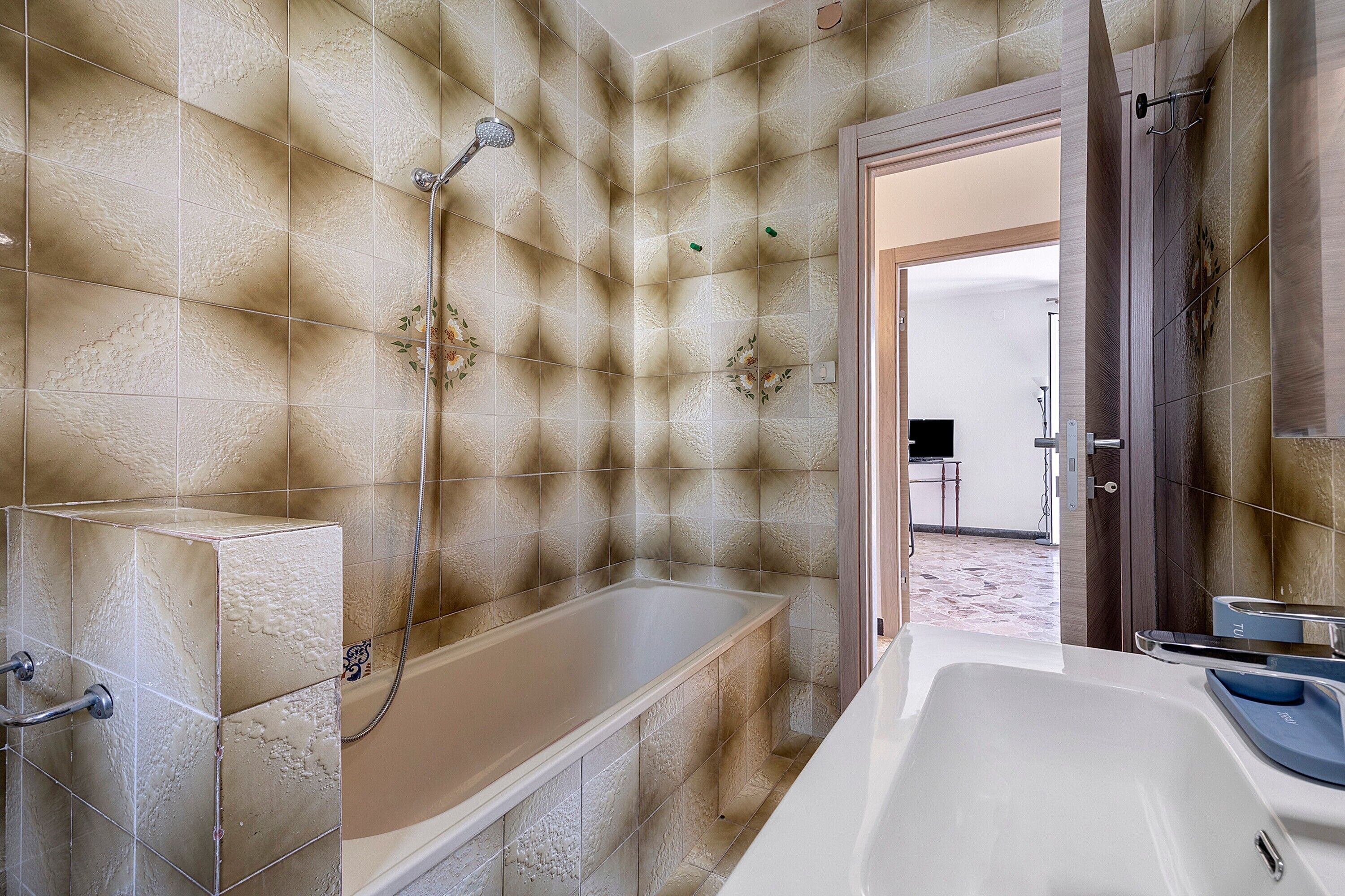 Ein Badezimmer mit einer Badewanne, einer Dusche und einer Tür zu einem weiteren Raum.