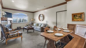 Un comedor con una mesa de madera preparada para cuatro personas, un sofá y un televisor al fondo.