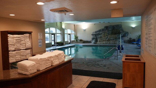 Zona de piscina con letrero de capacidad de spa, una pila de toallas y un mostrador de recepción.