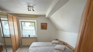 A bedroom with a bed, a window, a radiator, and a ceiling fan. - Holiday Home Milan with Private Terrace and Garden (Holzminden)