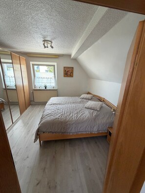 A bedroom with a bed, a window, a radiator, and a ceiling fan.