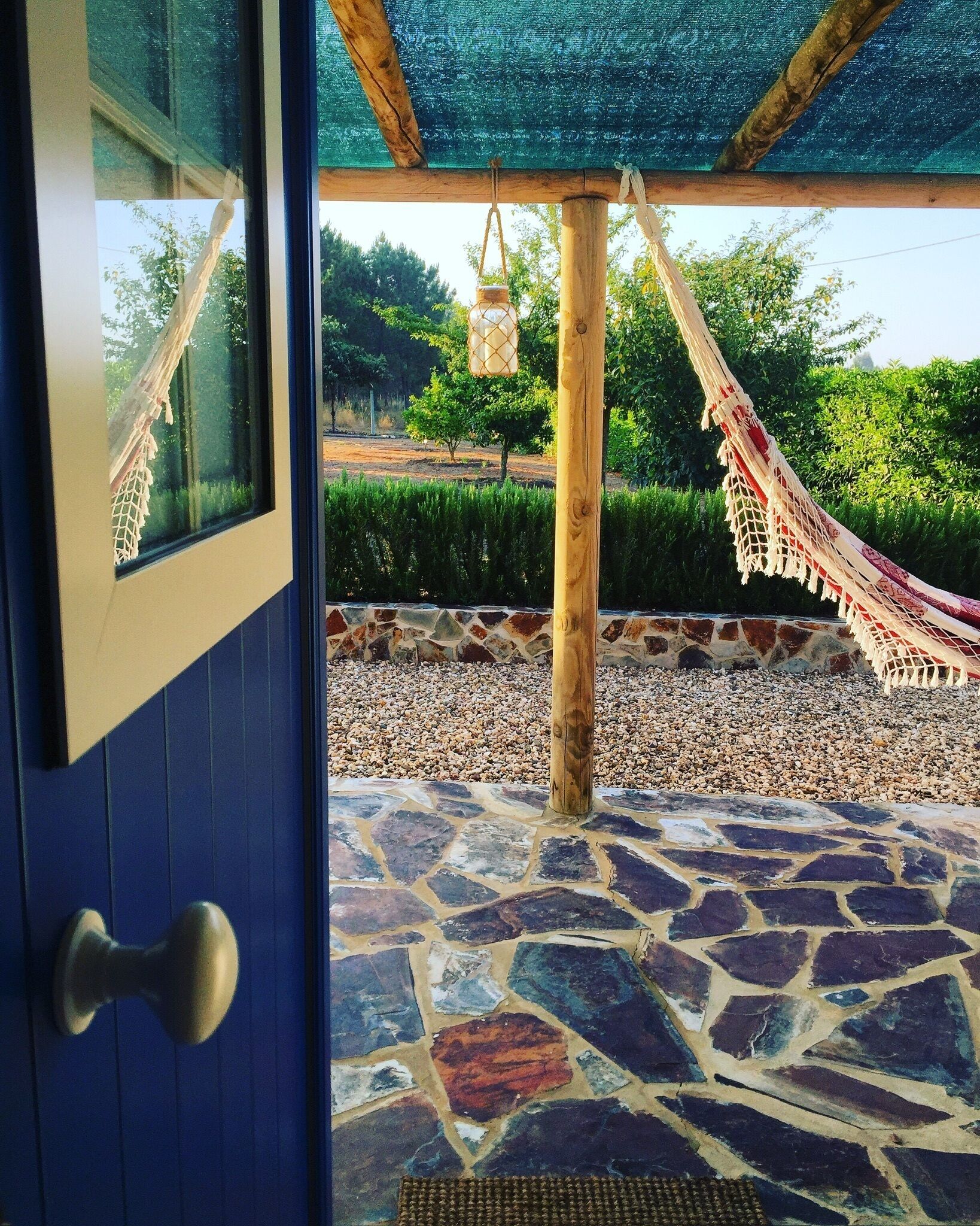 A doorway leading to a stone-tiled patio with a hammock and hanging lantern.
