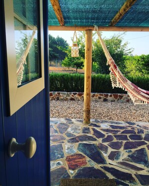 A doorway leading to a stone-tiled patio with a hammock and hanging lantern. - Monte Alentejano in Odemira, featuring a secluded house on private property. (Odemira)
