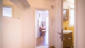 Käytävän päästä on pääsy ruokailutilaan, jossa on pöytä ja tuoleja, ja siellä on myös kylpyhuone, jossa on pesuallas ja kaappeja.