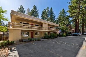 A two-story motel with a parking lot, surrounded by trees. - Your Tahoe Adventure Basecamp Near Heavenly — Midweek Discounts (South Lake Tahoe)