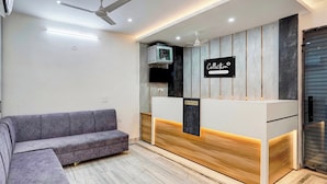 Un espace d’accueil comprenant un comptoir de réception, un canapé et un ventilateur de plafond.