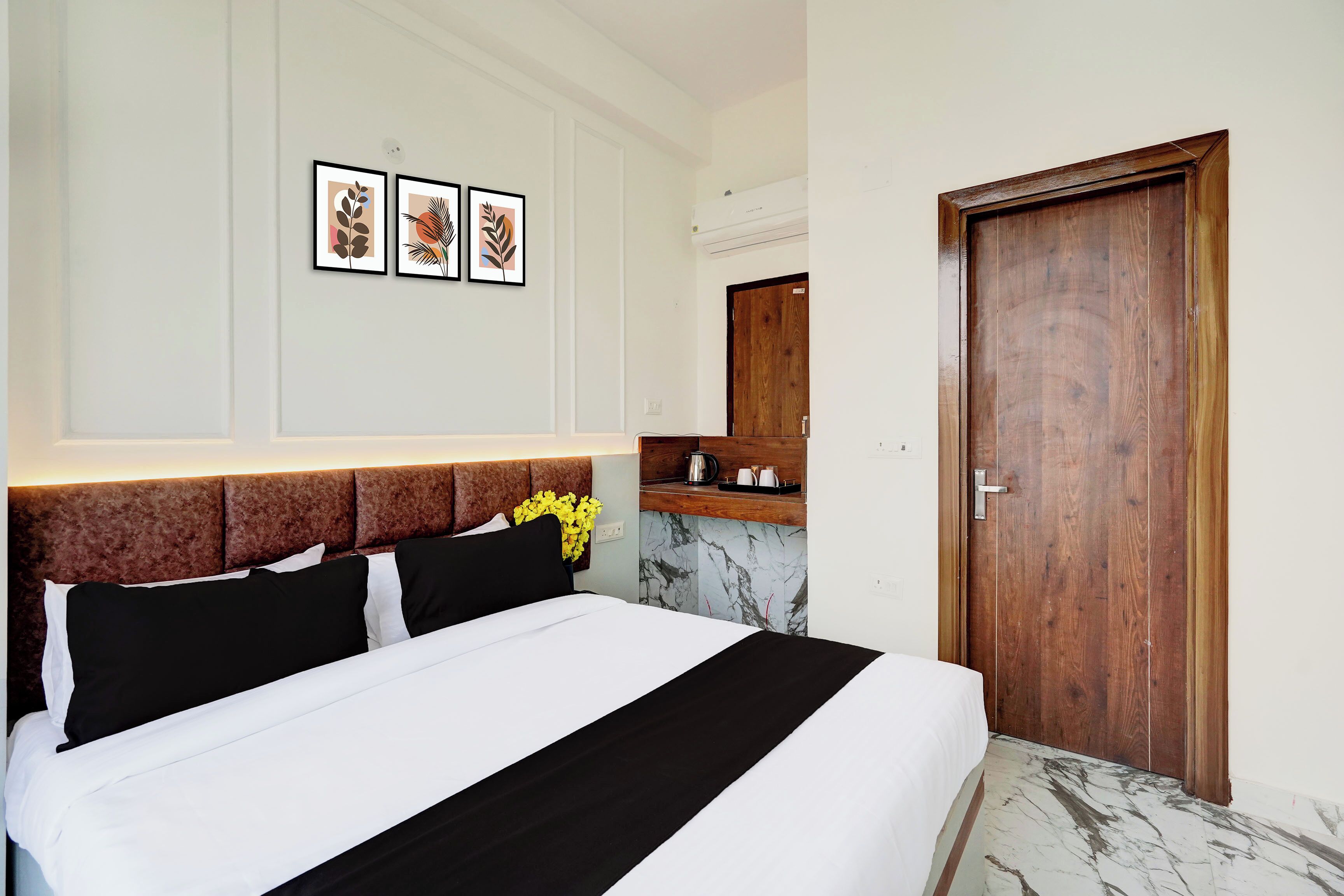Quarto de hotel com uma cama, uma porta de madeira, piso de mármore e uma prateleira com espelho fixada na parede.