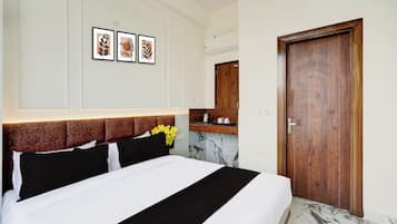 Quarto de hotel com uma cama, uma porta de madeira, piso de mármore e uma prateleira com espelho fixada na parede.