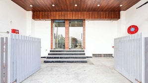 Une entrée d’immeuble avec un plafond en bois, des portes en verre et des portails en métal.