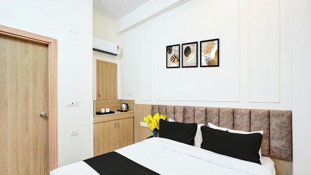 Une chambre d’hôtel comprenant un lit, une armoire en bois, une kitchenette et un climatiseur fixé au mur.