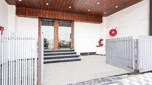 Une entrée d’immeuble avec un plafond en bois, des portes en verre et une lance d’incendie rouge.