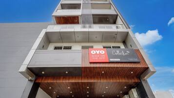 A modern building with a prominent OYO Collection sign, indicating a booking option via app.