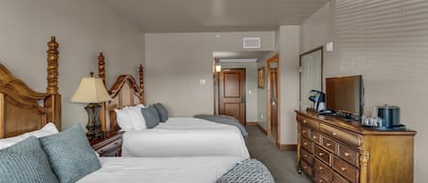 Une chambre d’hôtel avec deux lits, une commode, un téléviseur et une lampe.